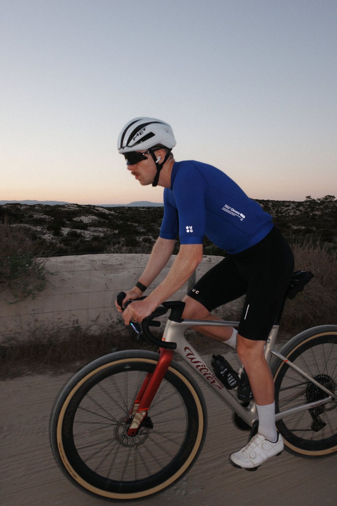 Grant riding a gravel road through the dunes at dusk